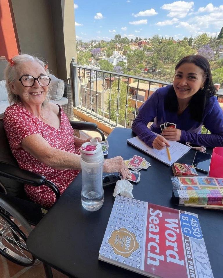 Paciente y cuidadora jugando cartas en una terraza