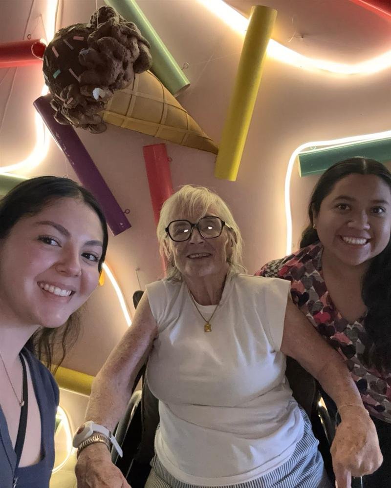 Paciente con dos cuidadoras sonriendo en una heladería